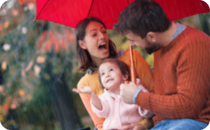 Un couple abrité sous un parapluie avec leur enfant