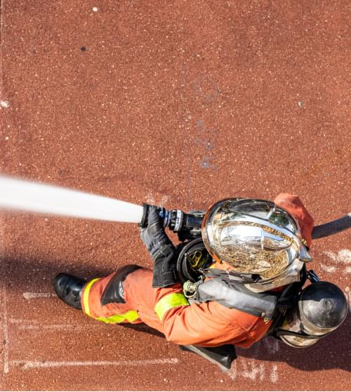 Deux sapeurs-pompiers volontaires éteignent un feu avec une lance à incendie assurance pompiers volontaires